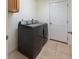 Functional laundry room featuring a modern washer and dryer set, tile flooring, and convenient access door at 4995 County Road 121D, Wildwood, FL 34785