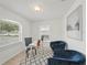 Inviting office space featuring a stylish desk, comfortable blue chairs, and ample natural light from two windows at 4995 County Road 121D, Wildwood, FL 34785