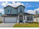 Charming two-story home featuring a blue exterior, well-manicured lawn, and an attached two-car garage at 6074 Sacred Oak Ave, Mount Dora, FL 32757
