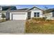 One-story home with white garage door and gray pavers driveway at 5938 Bristle Oak St, Mount Dora, FL 32757