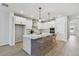 Modern kitchen boasts an island with barstool seating, stainless steel appliances, and white cabinetry at 5938 Bristle Oak St, Mount Dora, FL 32757