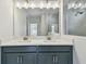 Close-up of bathroom featuring double vanity with white countertop and grey cabinets and tiled shower at 6063 Sacred Oak Ave, Mount Dora, FL 32757