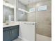 Bathroom featuring a vanity with grey cabinets and tiled shower with glass partition and window at 6063 Sacred Oak Ave, Mount Dora, FL 32757