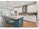Modern kitchen featuring a large island with bar seating, white cabinets, stainless steel appliances, and stylish lighting at 6063 Sacred Oak Ave, Mount Dora, FL 32757