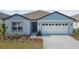 One-story home with light blue and white exterior, two-car garage, and landscaping at 486 Pine Tree Blvd, Lake Alfred, FL 33850