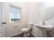 Modern half bath with pedestal sink, round mirror, and window, featuring stylish wood-look floors at 13465 Leaping Water Way, Astatula, FL 34705