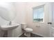 Half bath featuring a pedestal sink, toilet, modern fixtures, and a window at 13485 Leaping Water Way, Astatula, FL 34705