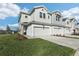 Modern townhome exterior featuring a two-car garage, white brick accents and green lawn at 520 Astera Winds Ln, Lake Mary, FL 32746