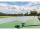Outdoor tennis court with a green and blue playing surface, surrounded by fencing and lush greenery at 2024 Capri Ln, Mount Dora, FL 32757