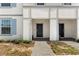 Close-up of townhome entrances with dark doors, brick walkways, and tidy landscaping at 7614 Oak Spring Ln, Davenport, FL 33837
