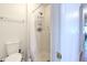 A modest bathroom featuring a walk-in shower with white tile, a toilet, and a partial view of the hallway at 169 Vista View Ave, Eagle Lake, FL 33839