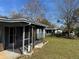 Cozy backyard featuring a screened porch with a concrete patio and a lush lawn surrounded by mature trees at 1224 10Th St, Holly Hill, FL 32117