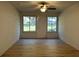 Cozy living room with wood floors, a ceiling fan, and lots of natural light from surrounding windows at 17729 Se 114Th Ct, Summerfield, FL 34491