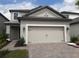Beige two-car garage door in the front of a gray two-story home with a paved brick driveway and walkway at 1263 Verdant Glade Pl, Winter Park, FL 32792