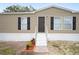 Tan mobile home with dark shutters, white steps, and small landscaped area at 3046 Crystal Hills Dr, Lakeland, FL 33801