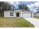 White house with gray roof, black door, and two-car garage at 1305 Congo Ct, Poinciana, FL 34759