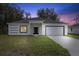 White house with gray roof, black door, and two-car garage at dusk at 1305 Congo Ct, Poinciana, FL 34759