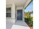 Inviting front entrance with a stylish blue door, covered porch, and manicured landscaping at 9076 Wildlight Trl, Wildwood, FL 34785