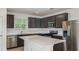Modern kitchen features stainless steel appliances, dark wood cabinets, a white countertop island, and tiled floors at 9076 Wildlight Trl, Wildwood, FL 34785