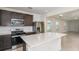 Open-concept kitchen with stainless steel appliances, dark cabinets, island with white countertops, connecting to the living area at 9076 Wildlight Trl, Wildwood, FL 34785