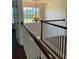 Upstairs hallway with hardwood floors, chandelier, and railing overlooking entryway at 899 W Lake Marion Rd, Haines City, FL 33844