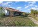 Spacious backyard features a well-maintained lawn, mature trees, and a walkway leading to a sunroom at 6141 Palmetto Dr, Indian Lake Estates, FL 33855