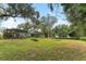 Spacious backyard with large grassy area, mature trees, and screened enclosure at 1614 King James Ct, Lakeland, FL 33813