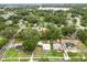 An aerial view shows the home situated on a lot with mature trees and proximity to a lake at 415 Avenue K Ne, Winter Haven, FL 33881