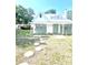 Charming home featuring a metal roof, white exterior with green trim, stepping stones and mature trees at 415 Avenue K Ne, Winter Haven, FL 33881