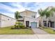 Two-story home with light beige walls and stone accents, a teal garage door, and landscaped yard at 601 Drop Shot Dr, Davenport, FL 33896