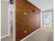 Home hallway with exposed brick feature wall, carpet flooring, and access to bedrooms at 1463 Myrtlewood St, Davenport, FL 33896
