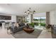 Spacious living room with a large window, gray sofa, and wooden coffee table at 264 Woodsage Pl, Lake Alfred, FL 33850