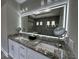 Bright bathroom featuring a double vanity with granite countertops and a large, illuminated mirror at 7833 Freestyle Ln, Winter Garden, FL 34787
