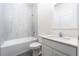 Bright bathroom showcases modern white vanity with a tub and shower featuring neutral tiling at 308 Bass Ct, Poinciana, FL 34759