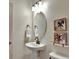 Elegant powder room with pedestal sink, oval mirror, and framed art at 8710 Hinsdale Heights Dr, Polk City, FL 33868