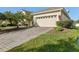 Home featuring a stone driveway, a beige multi-car garage, and manicured landscaping at 4026 Navigator Way, Kissimmee, FL 34746