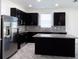 Modern kitchen with dark cabinetry, granite counters, and stainless steel appliances at 2180 Nighthawk Dr, Haines City, FL 33844