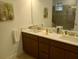 A spacious bathroom vanity with double sinks, dark wood cabinetry and decorative plants for a spa-like feel at 621 San Augusto Dr, Poinciana, FL 34759