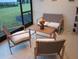 A cozy screened-in patio features stylish outdoor seating with cushioned chairs and a small wooden table at 621 San Augusto Dr, Poinciana, FL 34759
