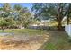 Large backyard with grassy area, mature trees, and wooden fence at 631 Swiss Dr, Lakeland, FL 33810