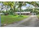 Ranch house with long driveway, green lawn, and mature trees at 1528 Walker Rd, Lakeland, FL 33810