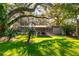 Sunny backyard with covered patio, pool, and large trees at 6104 Irby W Ln, Lakeland, FL 33811