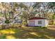 Detached garage with gray door, red trim, and lush landscaping at 6104 Irby W Ln, Lakeland, FL 33811