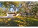 Ranch-style home with attached garage and large oak trees at 6104 Irby W Ln, Lakeland, FL 33811