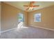 A bright bedroom featuring neutral paint, carpeted floors, a ceiling fan, and two windows at 1507 Hontoon Rd, Deland, FL 32720