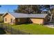 Rear exterior showcasing metal roof, fenced yard, and grass at 1507 Hontoon Rd, Deland, FL 32720