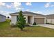 One-story house with a two-car garage and a tree in the front yard at 1734 Hill Top Dr, Dundee, FL 33838