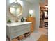 Bathroom with gray vanity, marble countertop, modern faucet, round mirror, and walk-in closet at 225 Temple Cir, Eustis, FL 32726