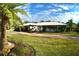 Side view of a single-story home with palm tree and lush lawn at 225 Temple Cir, Eustis, FL 32726