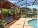 Inviting screened-in pool area featuring a wooden deck, outdoor seating, bar stools, and scenic views at 225 Temple Cir, Eustis, FL 32726